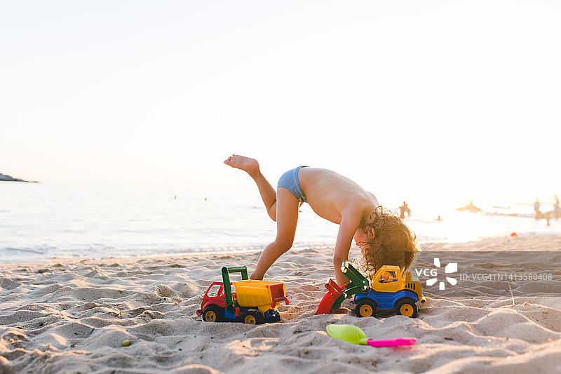 小男孩在沙滩上玩沙子图片素材