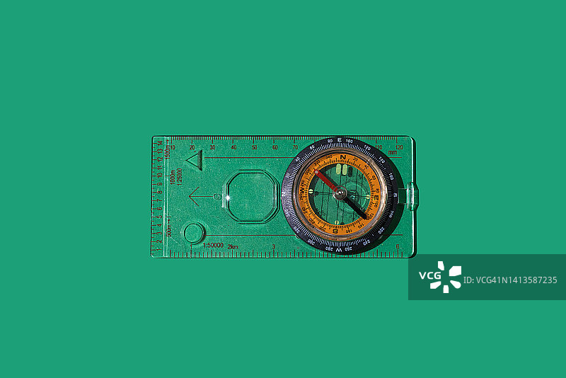 绿色背景上的塑料支架指南针与测量距离的尺子，户外定向、远足、露营和探索概念图片素材