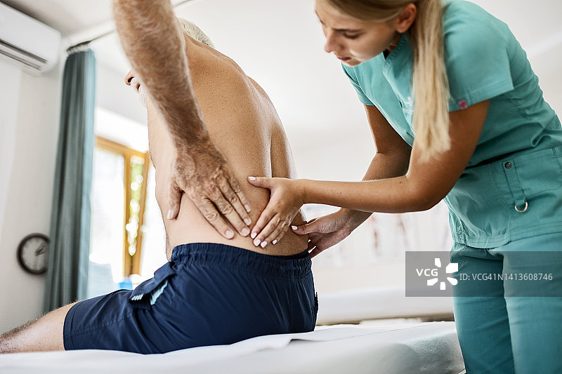 年轻理疗师帮助患者缓解背痛图片素材
