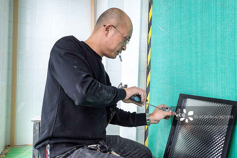 正在安装橱柜且吸烟的亚洲工人图片素材