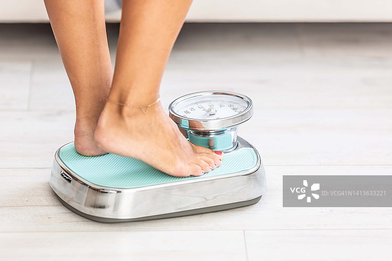 站在体重秤上的女人，腿部特写图片素材