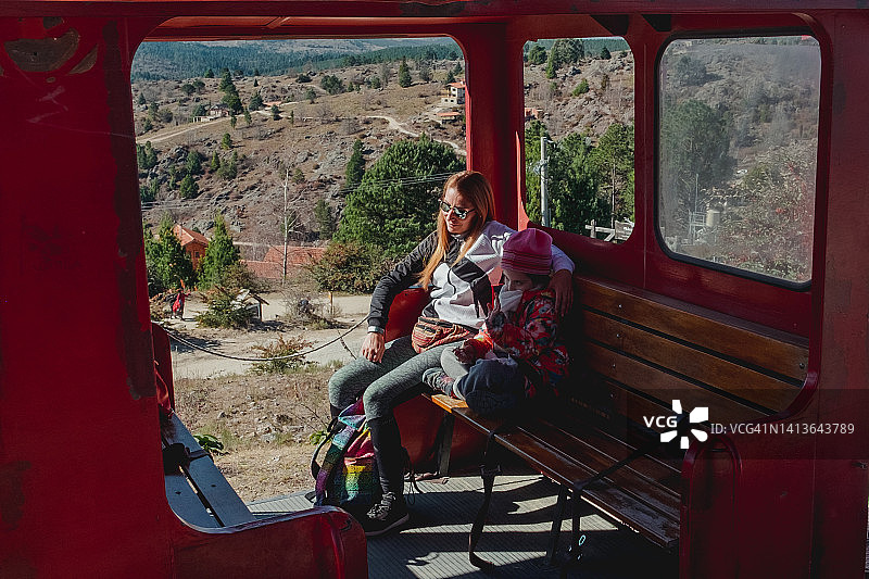 年轻母亲和女儿在阿根廷科尔多瓦的火车上欣赏冬季美景图片素材