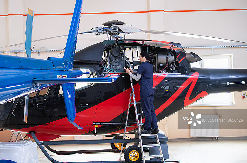 在机库研究直升机的女性航空工程师图片素材