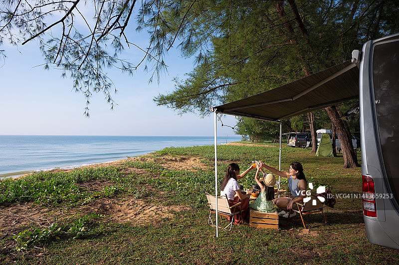 亚洲家庭开着露营车在海滩享受野餐和早餐图片素材