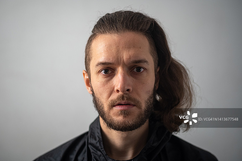 看着镜头的留着胡须长发的年轻白人男子图片素材