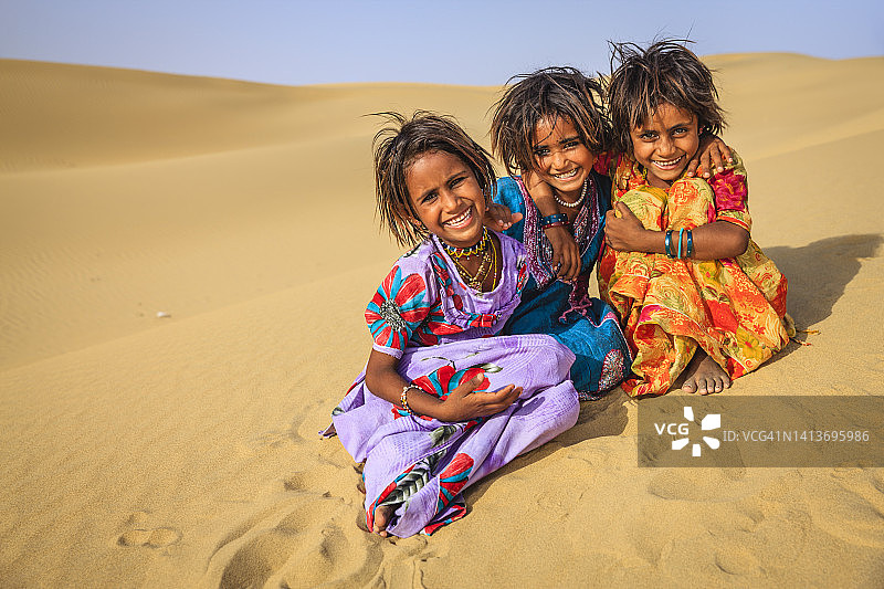 三个印度女孩在村庄附近的沙丘上玩耍，印度图片素材
