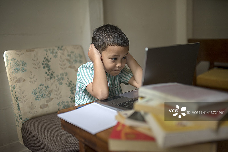 在笔记本电脑前表情困惑的亚洲儿童图片素材