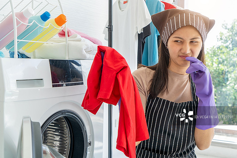 女人将脏臭的衣物放入白色洗衣机图片素材