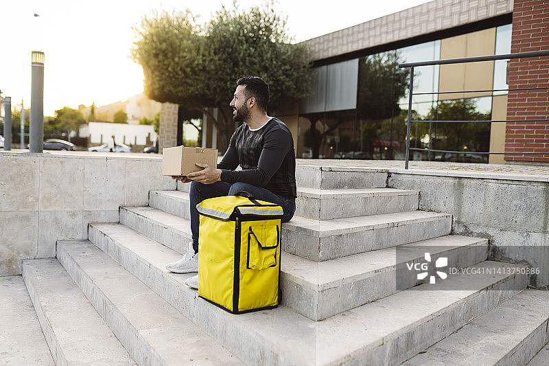 坐在楼梯上的快递员，包裹配送员正在休息图片素材