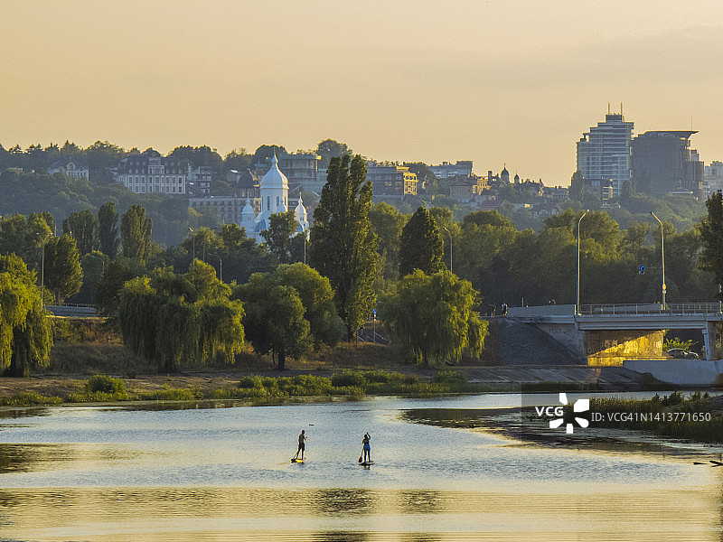 两人在皮划艇上划桨，基辅城市日落美景图片素材