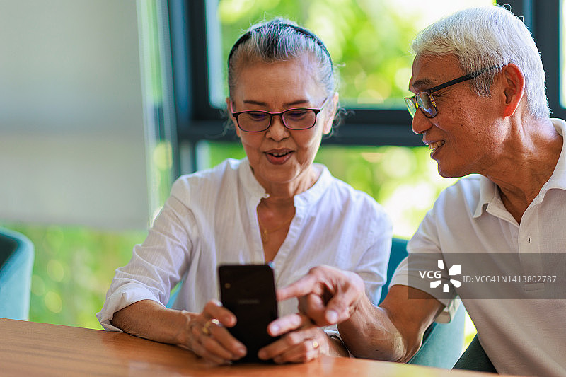 老年夫妇在客厅里使用智能手机图片素材