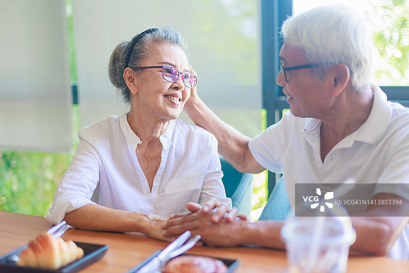 老年夫妇在餐桌上手牵着手图片素材