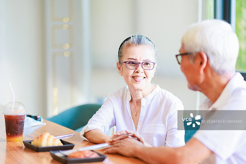 一对亚洲老年夫妇在餐厅享用特别的餐点。图片素材