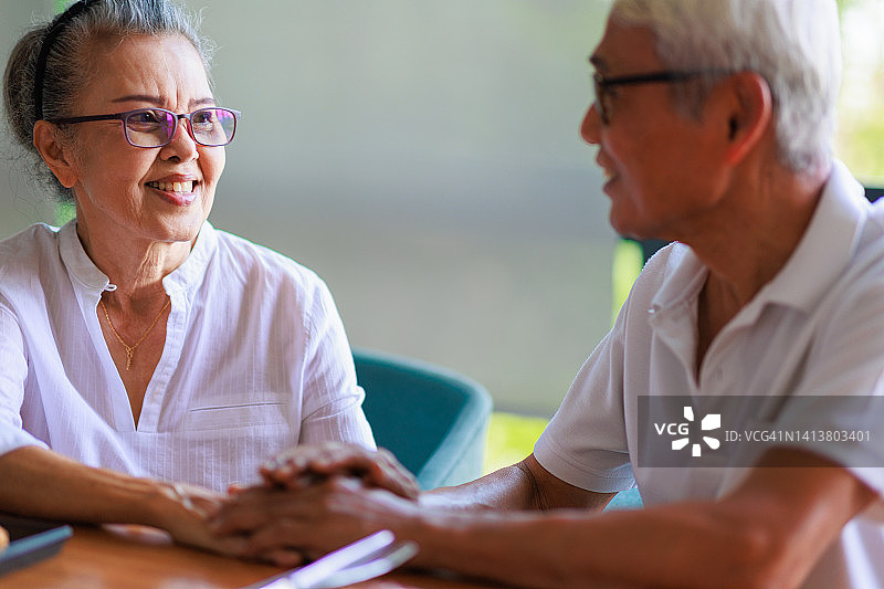 老年夫妇在餐桌上手牵着手图片素材