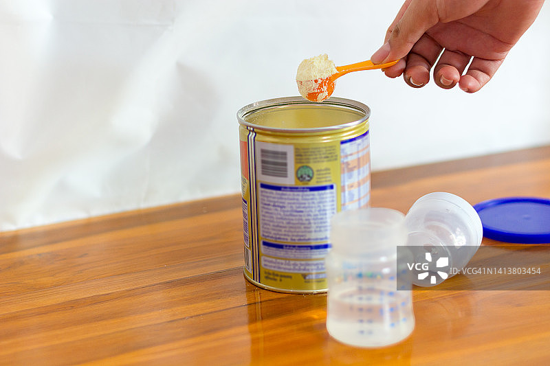 特写：浅色背景下的奶粉和蓝色勺子。罐中量勺里的婴儿奶粉，以及婴儿奶粉和奶瓶。图片素材