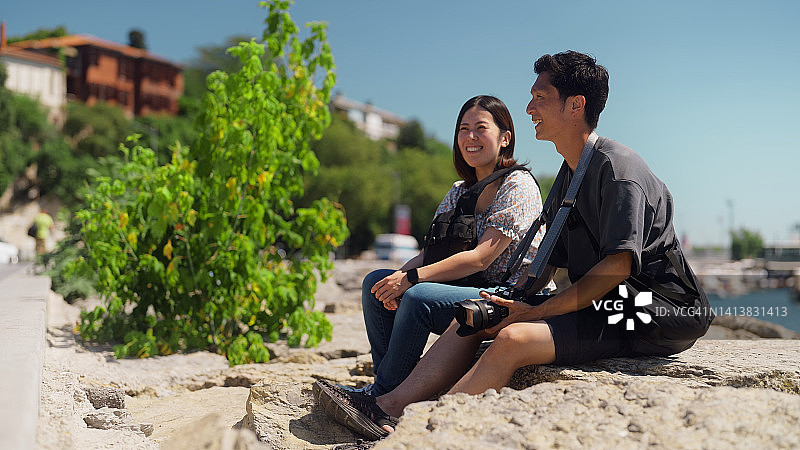 旅行期间坐在海边的两名年轻游客图片素材