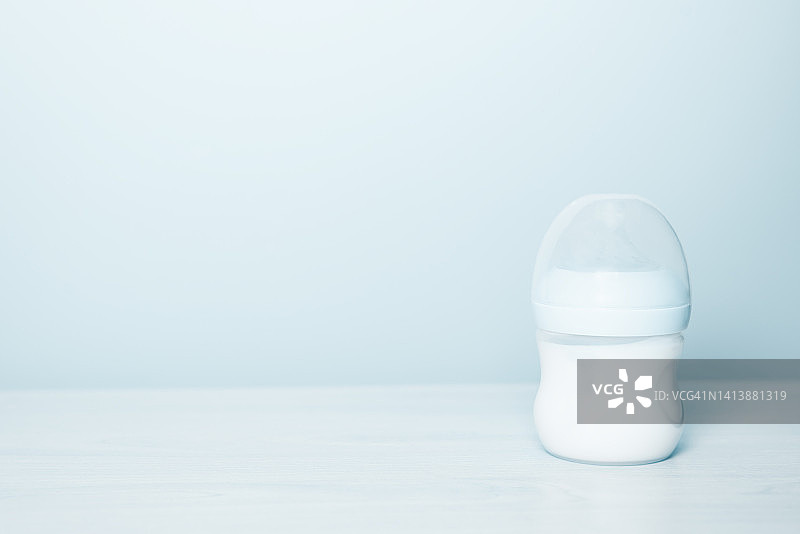 新生儿牛奶瓶：蓝色背景，留白图片素材
