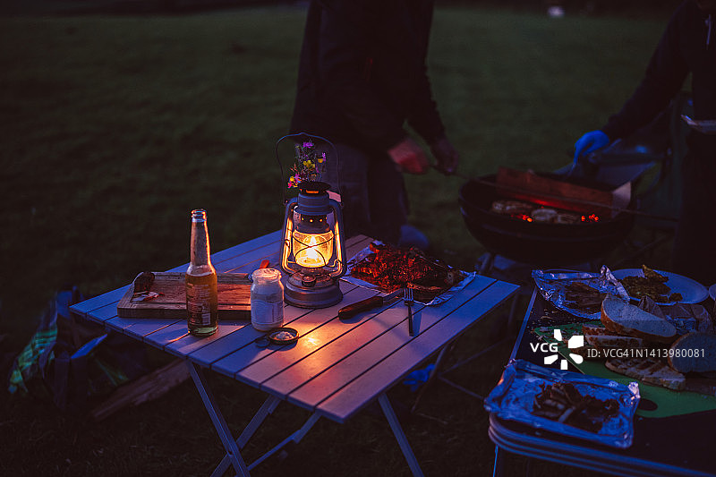 黄昏露营地肉类野餐桌和油灯特写图片素材