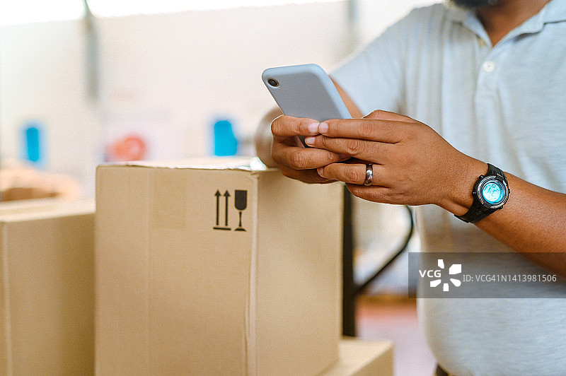 运输、交付和物流工人正在用手机发短信并组织订单。仓库中包裹或箱子快递员员工在线上和通过社交媒体与客户聊天的特写镜头图片素材