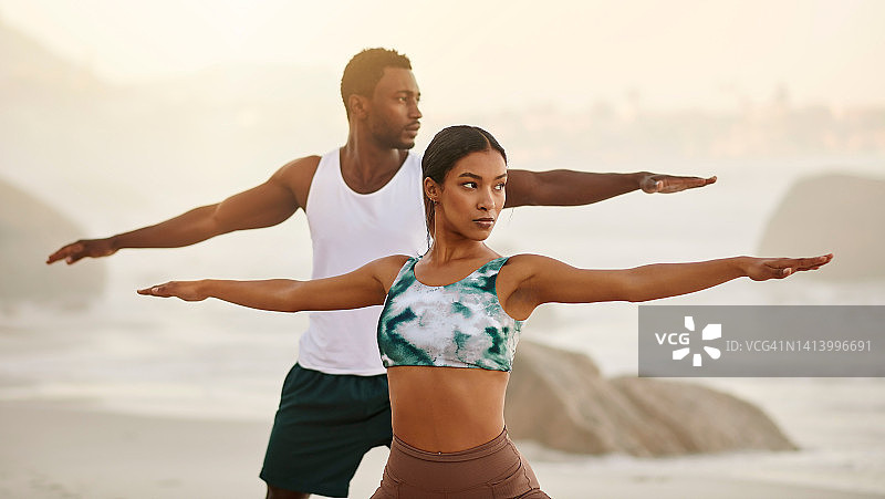 海边瑜伽情侣：战士姿势伸展运动图片素材