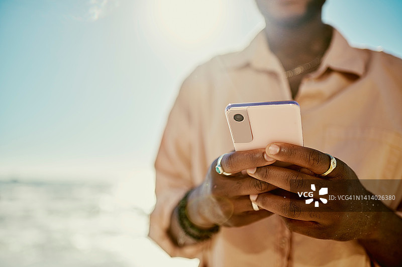时尚的男人在度假时发短信或更新社交媒体帖子图片素材