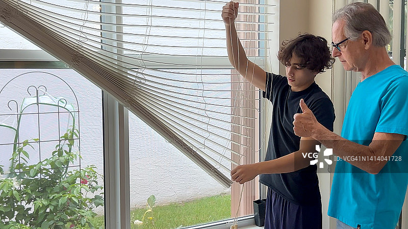 拉丁裔祖父和孙子修理破损的遮阳篷图片素材