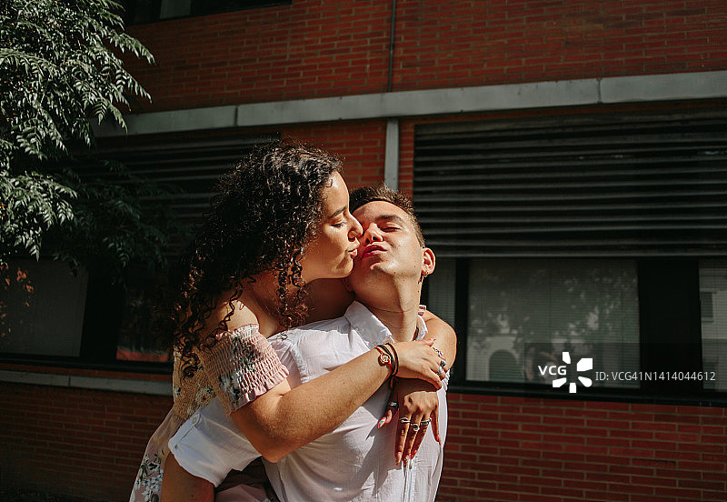 年轻男子背着女朋友，两人都抬头看的肖像。相爱的情侣。英俊的男人背着他的女朋友图片素材