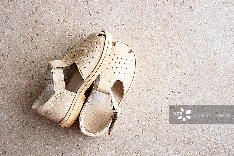 复古米色婴儿凉鞋，混凝土背景俯视图，留白图片素材