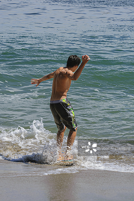 在海浪中玩耍的拉丁裔少年图片素材