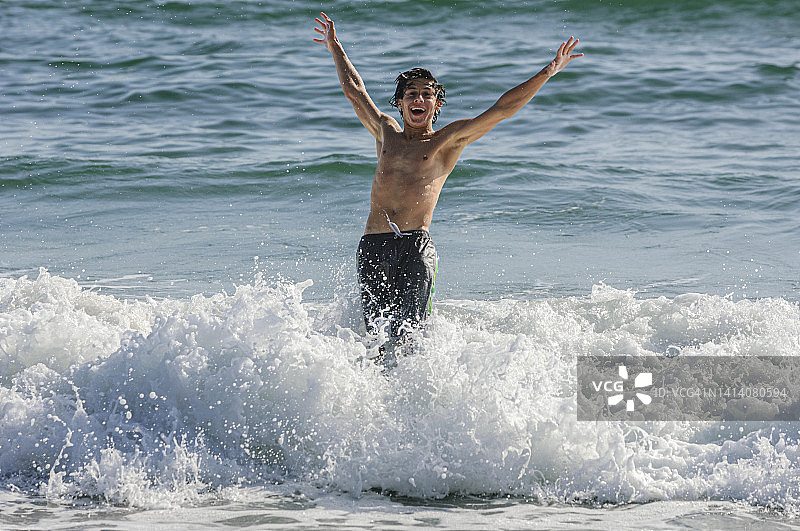 在海浪中玩耍的拉丁裔少年图片素材