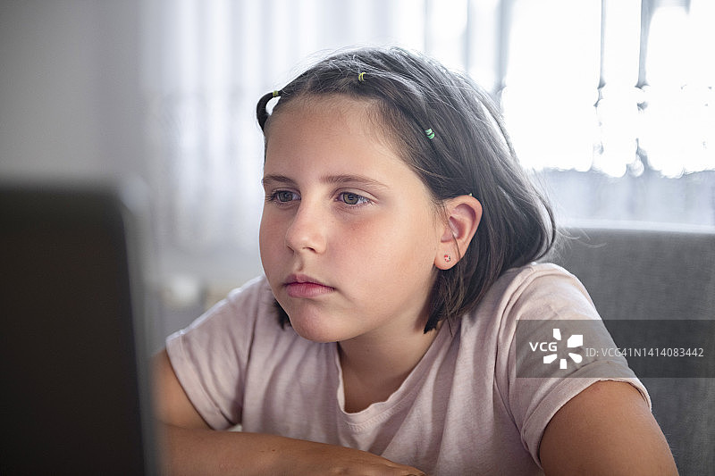 孩子在家用笔记本电脑学习和做作业。图片素材