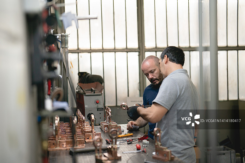 正在加工金属零件的蓝领工人和设计师图片素材