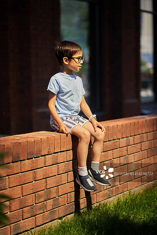 坐在砖墙边等待的男孩图片素材