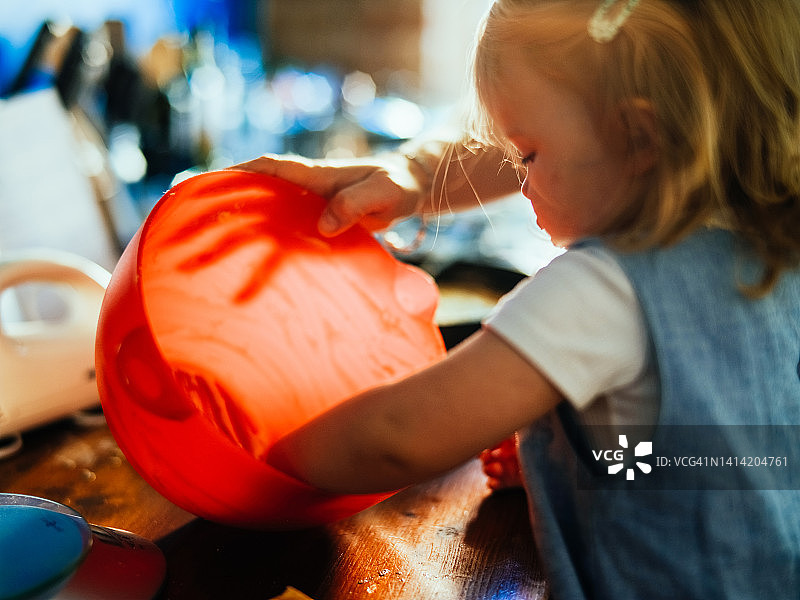 小女孩在家里的厨房品尝苹果蛋糕的新鲜面团图片素材
