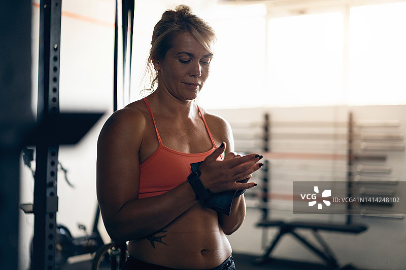 白人女运动员在健身房训练时调整腕带图片素材
