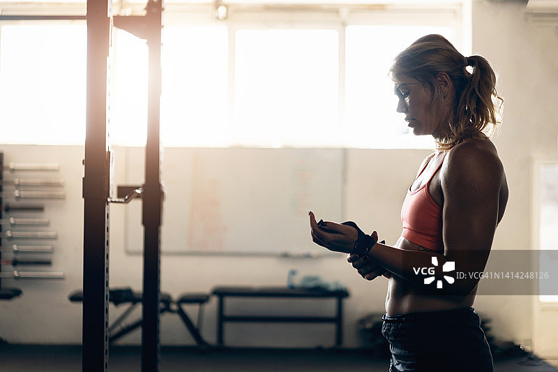白人女运动员在健身房训练时调整腕带图片素材