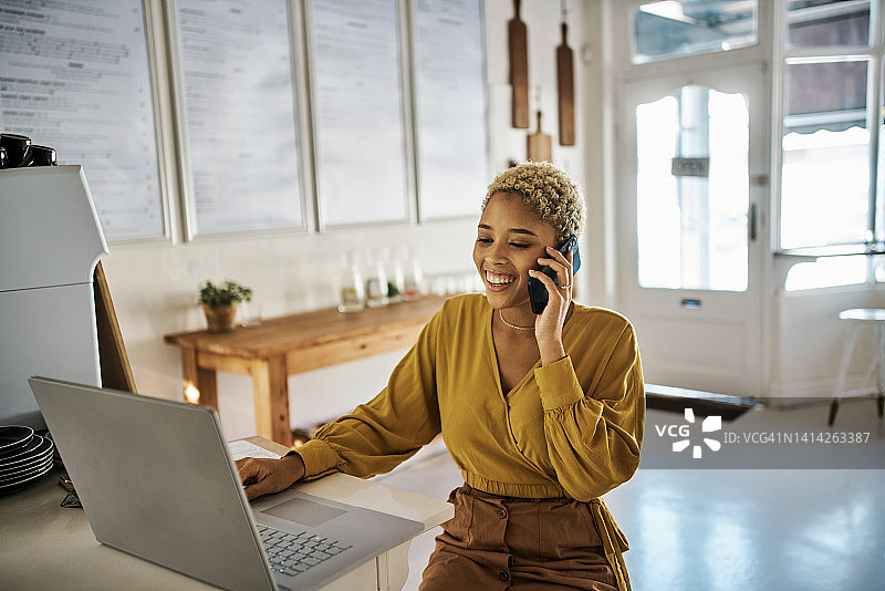 企业主在咖啡馆里通过电话和笔记本电脑接收在线订单图片素材