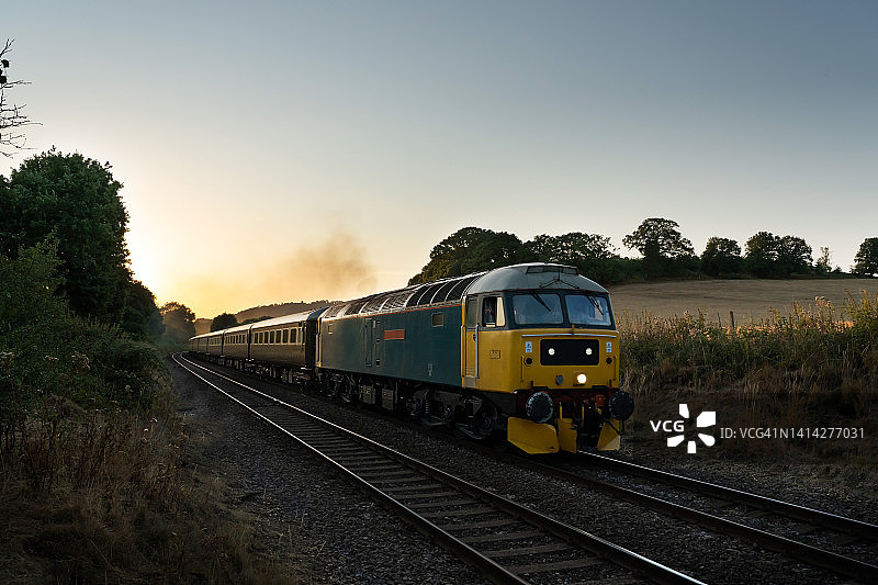 复古柴油火车在日落时分牵引普尔曼车厢穿过萨里山图片素材