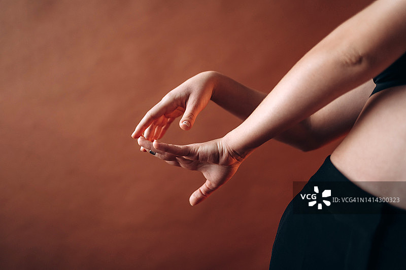 美丽女性的手在棕色墙壁背景下摆动姿势。女性气质和自然美概念。正面和特写图片素材