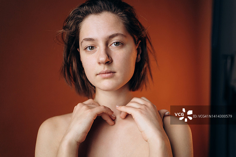 不戴胸罩的年轻女子看着镜头，抚摸着锁骨图片素材