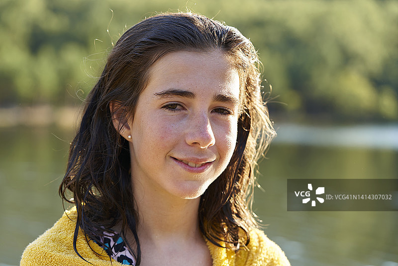 棕色湿发、肩披毛巾的白人女孩特写，面带微笑看向镜头图片素材