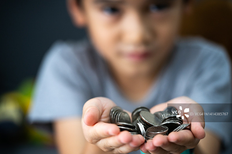 男孩拿着硬币，赡养费概念，金钱图片素材