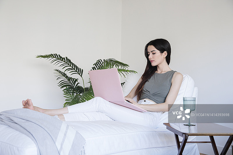 在家中扶手椅上使用笔记本电脑的女人图片素材