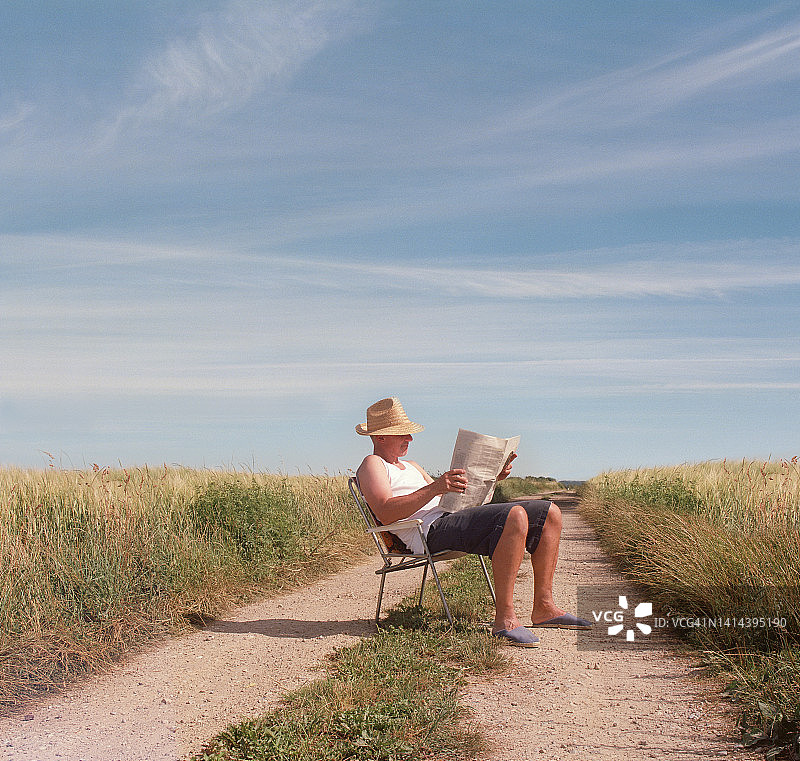 在玉米地旁看书的男人图片素材