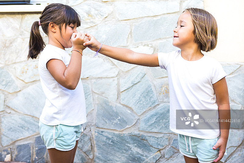 姐妹和朋友玩石头剪刀布，享受夏日乐趣图片素材