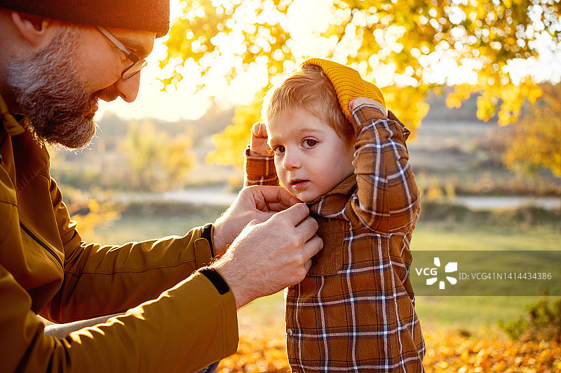白人父亲给幼儿儿子扣衬衫图片素材