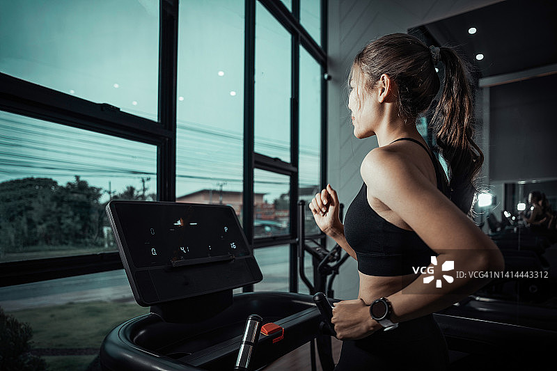 女人在健身房的跑步机上跑步，健身健康生活方式图片素材
