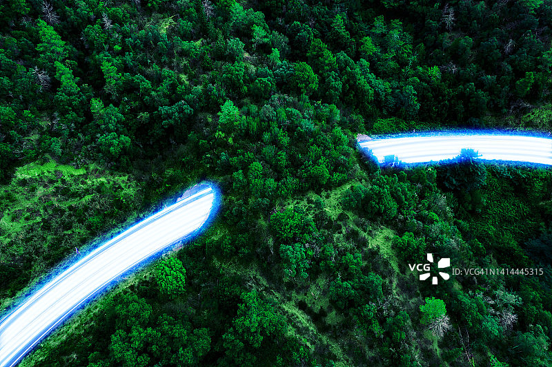 隧道和自然高速公路上快速流动的蓝色光轨与可持续零排放交通图片素材