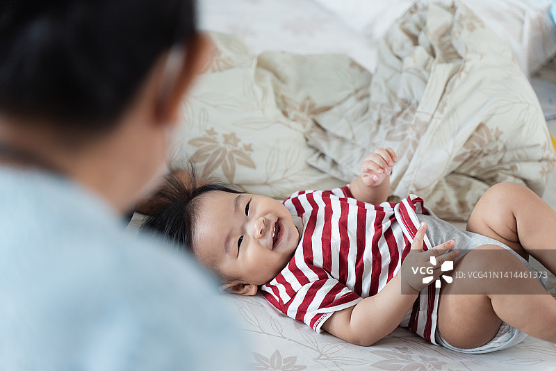 可爱的亚洲宝宝和祖父母在床上玩耍图片素材