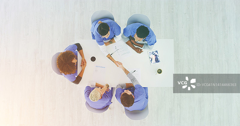 团队会议上医生握手，庆祝医疗突破成功、晋升或欢迎医护人员。自上而下，为晋升、成就或认可而握手图片素材